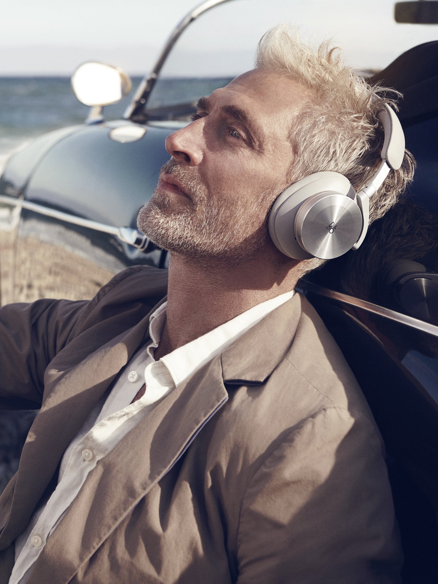 BeoPlay H95 in Grey Mist getragen von einem Mann am Strand