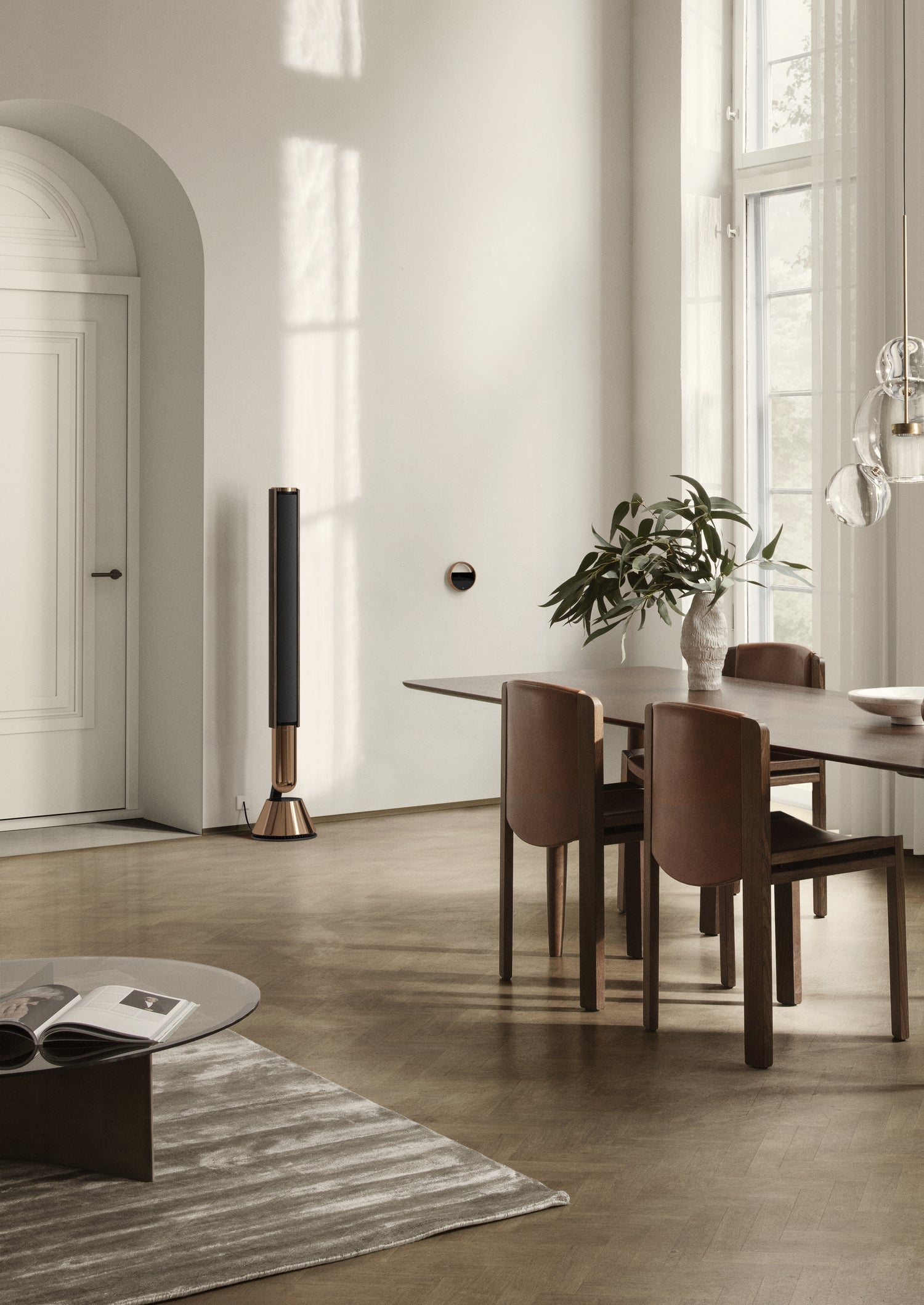 BeoLab 28 in Bronze mit einer BeoRemote Halo in Bronze an einer Wand