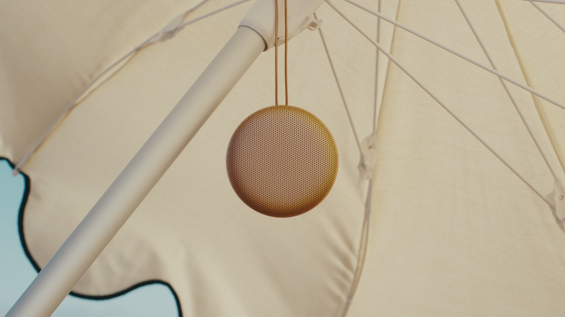 Bang & Olufsen B&O Beosound A1 3. Generation in Hones Tone am Strand hängend an einem Sonnenschirm