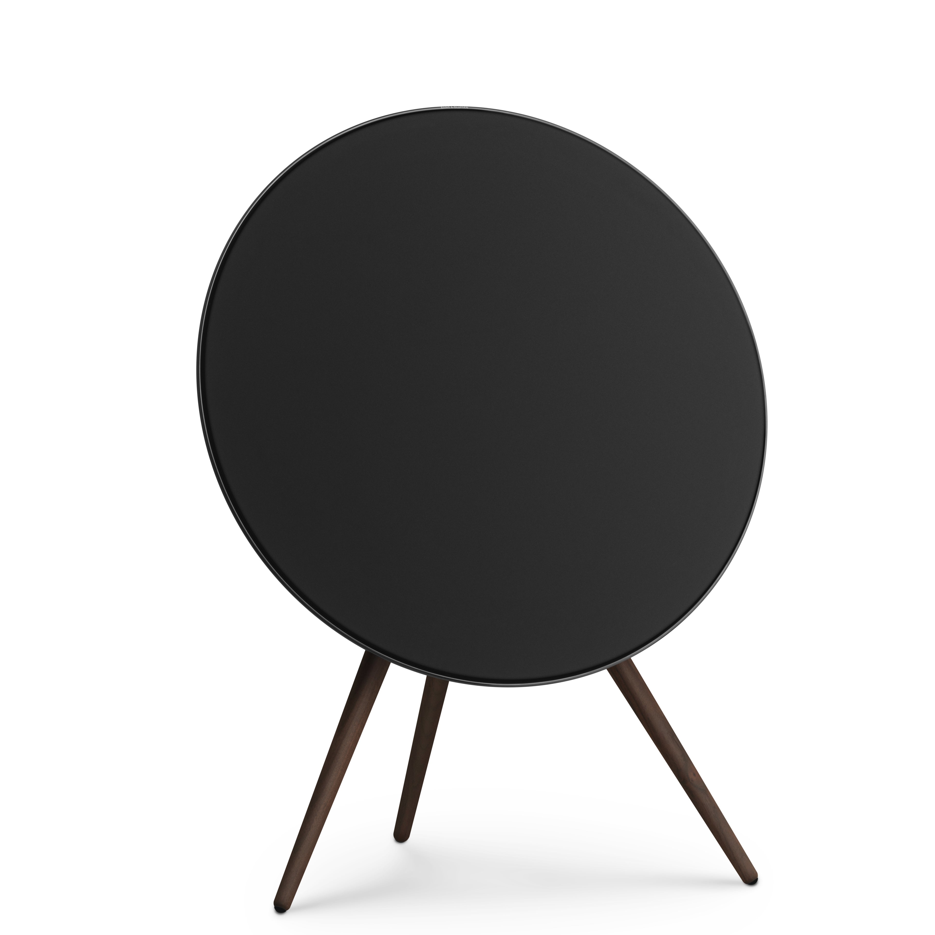 Profilansicht der Bang & Olufsen Beosound A9 in Black Anthracite aus einer Dreiviertel-Perspektive. Die Kombination aus schwarzem Textilbezug, anthrazitfarbenem Aluminiumring und Stativbeinen aus dunklem Nussbaumholz unterstreicht das elegante, maskuline Design. 