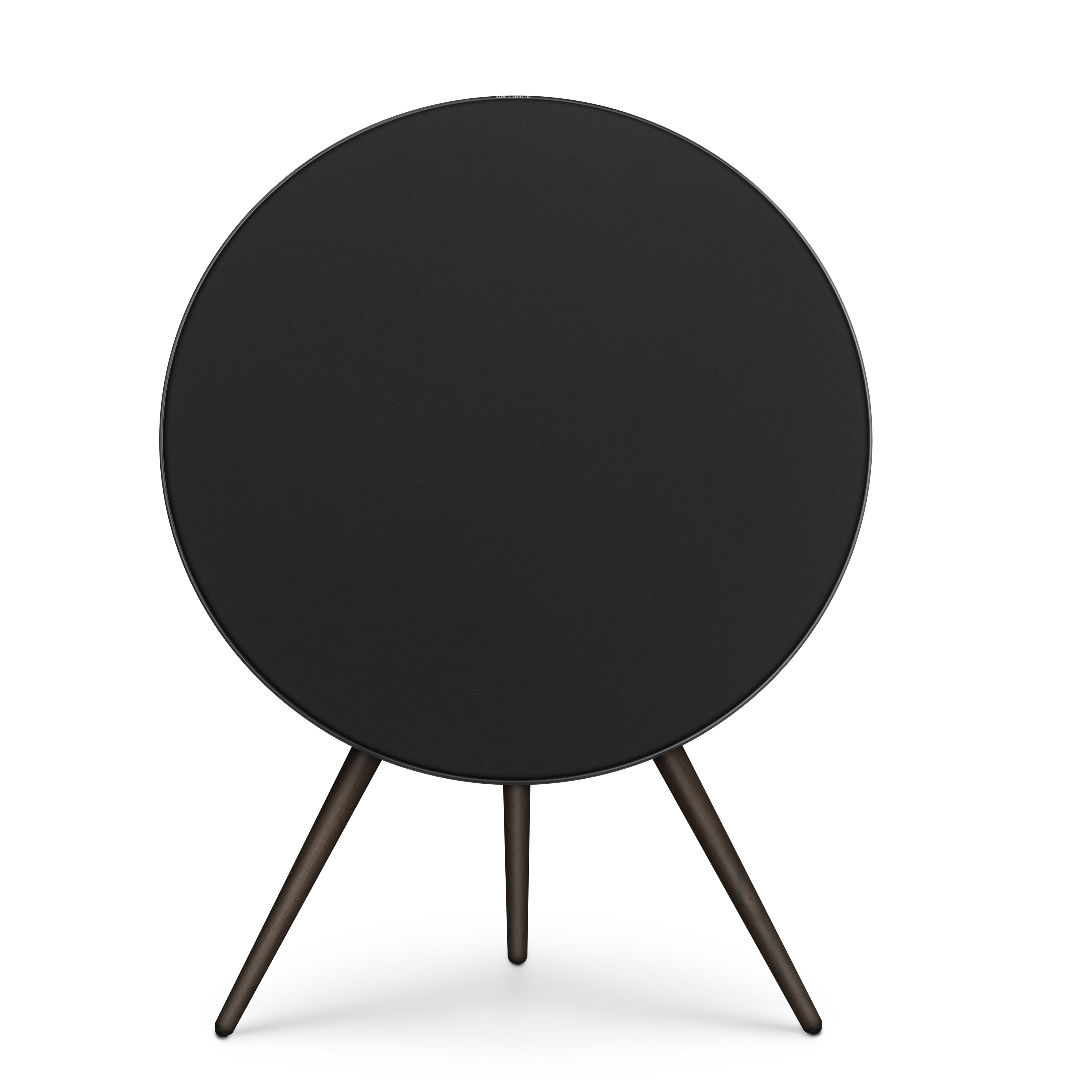 Frontale Studio-Aufnahme der Bang & Olufsen Beosound A9 in der Ausführung Black Anthracite. Das kreisrunde Design besticht durch eine tiefschwarze Textilfront, einen anthrazitfarbenen Aluminiumrahmen und drei elegante Standbeine aus dunklem Nussbaumholz. Ein kraftvolles Designobjekt für modernste Interieurs, freigestellt auf Weiß.