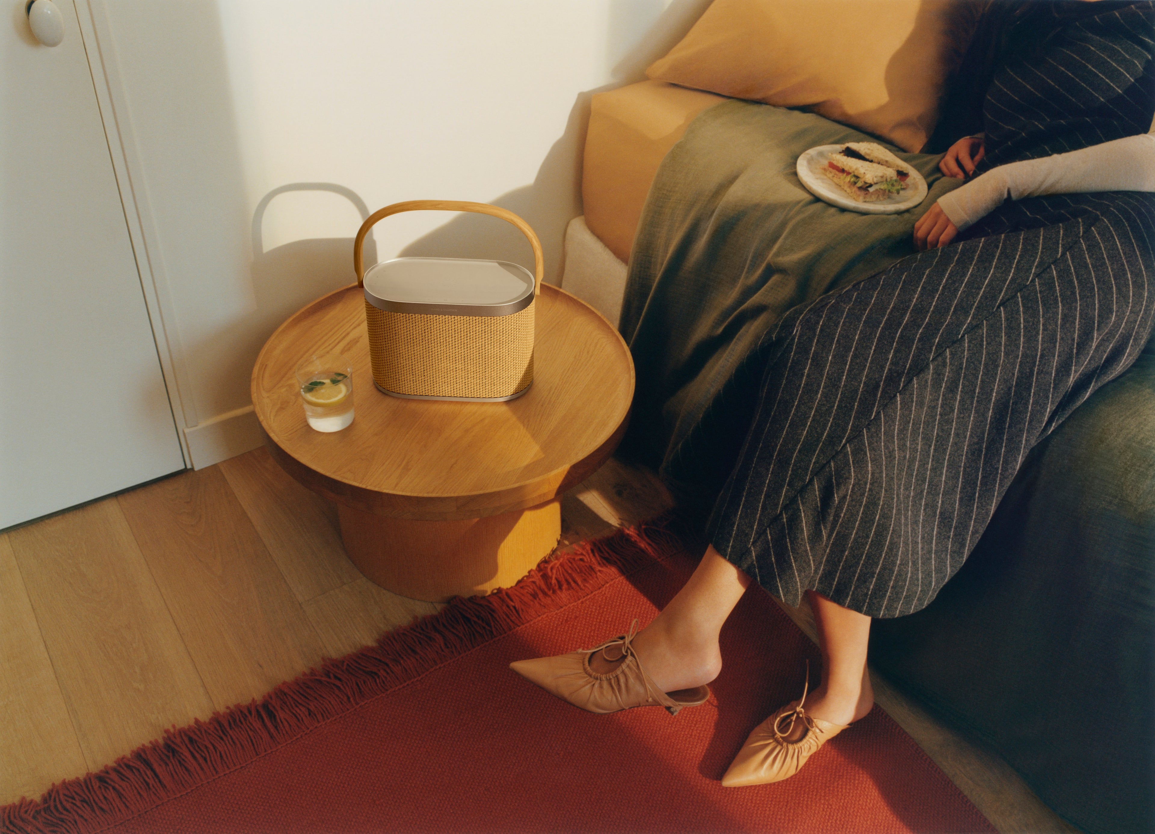 Bang & Olufsen Beosound A5 in Nordic Weave auf einem kleinen Beistelltisch an einem Sofa