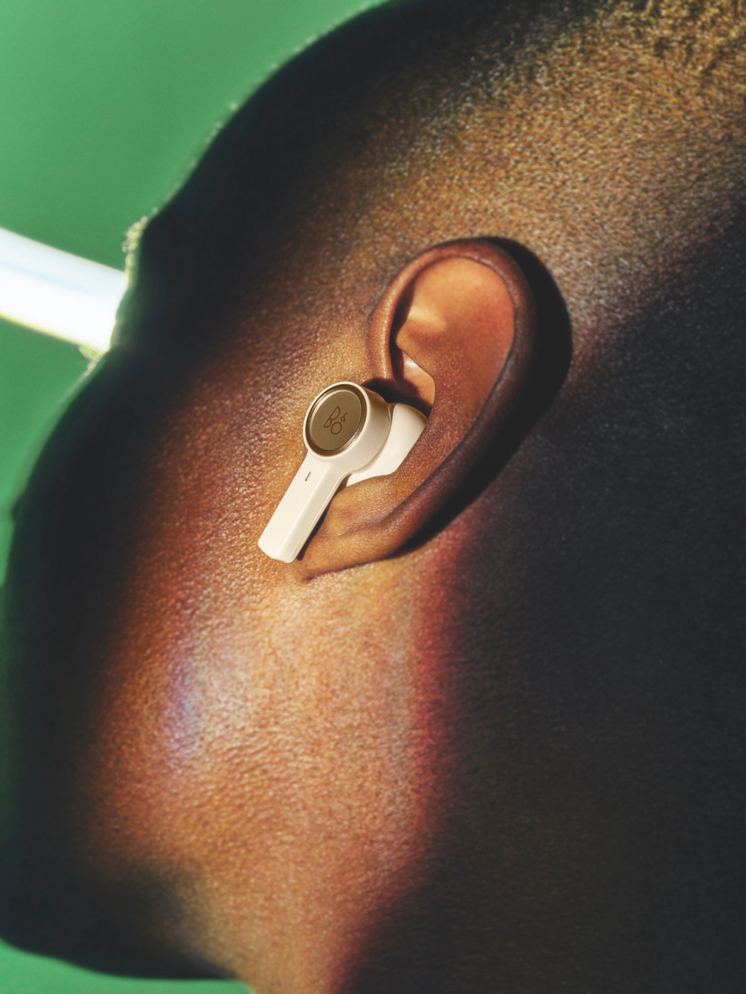 BeoPlay EX in Gold Tone im Ohr eines Mannes
