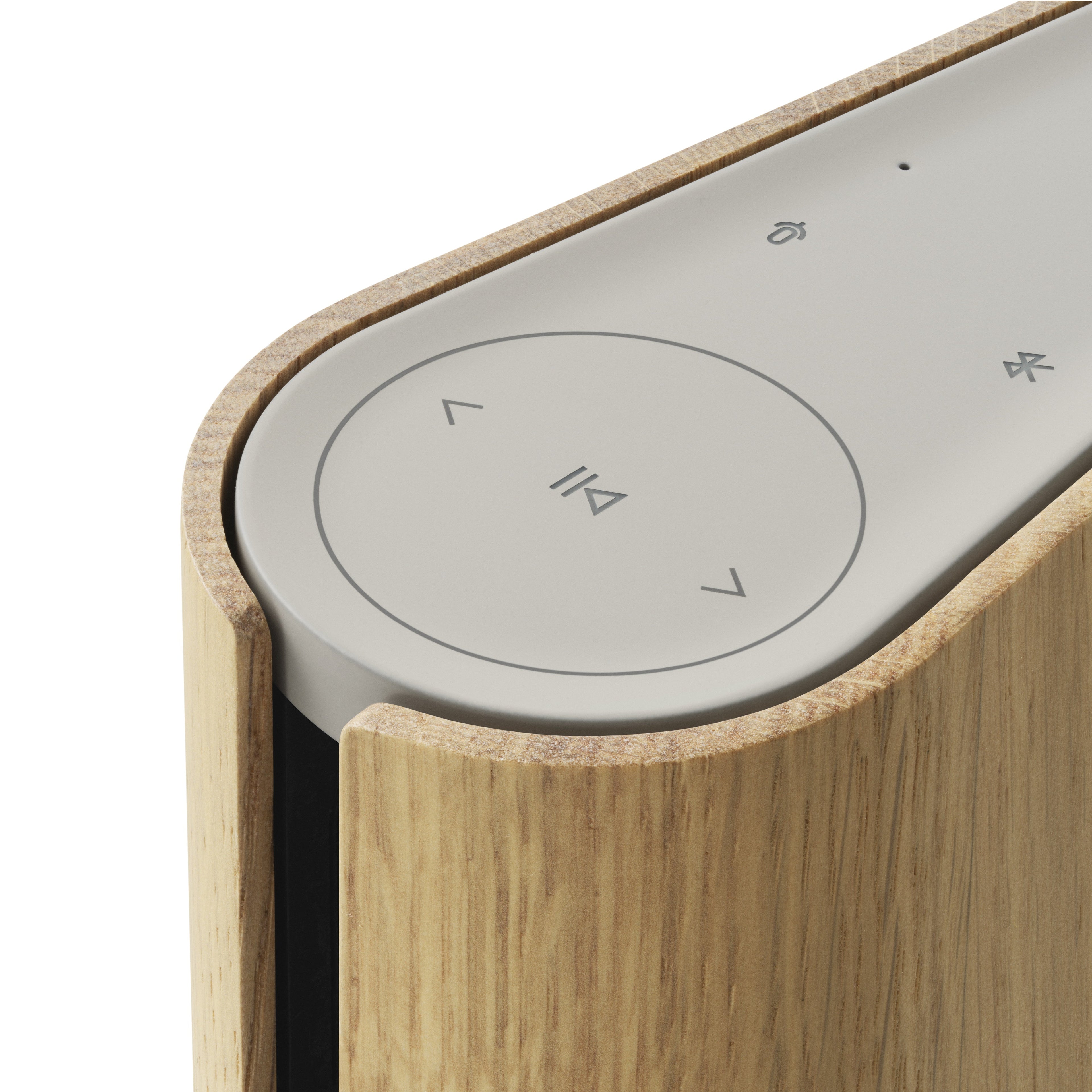 Nahaufnahme der intuitiven Touch-Bedienelemente auf der Oberseite des Beosound Emerge (Gold Tone). Symbole für Play/Pause, Lautstärke und Bluetooth sind dezent in die sandfarbene Oberfläche integriert.
