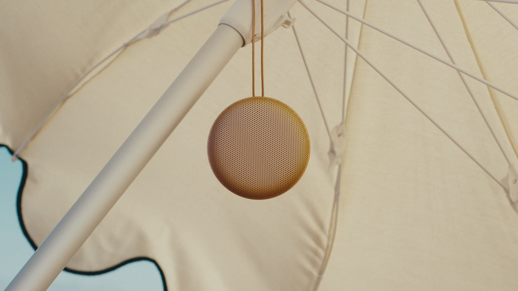 Bang & Olufsen B&O Beosound A1 3. Generation in Hones Tone am Strand hängend an einem Sonnenschirm