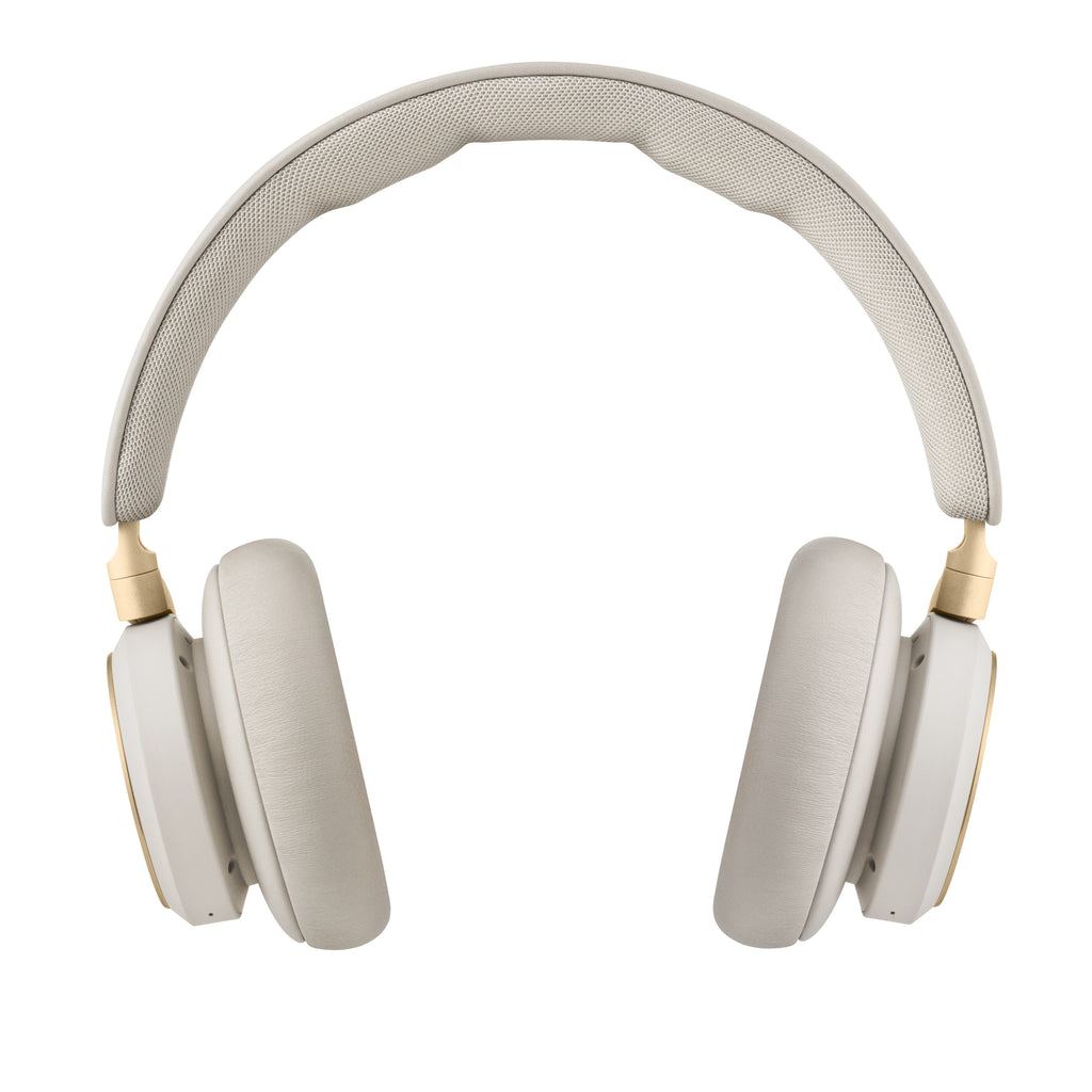 Frontale Studio-Ansicht des Bang & Olufsen Beoplay HX Over-Ear-Kopfhörers in der Farbe Sand vor weißem Hintergrund. Das Bild zeigt das weiche Lammleder-Polster des Kopfbügels und die voluminösen Ohrpolster, eingefasst von goldenen Aluminium-Elementen.