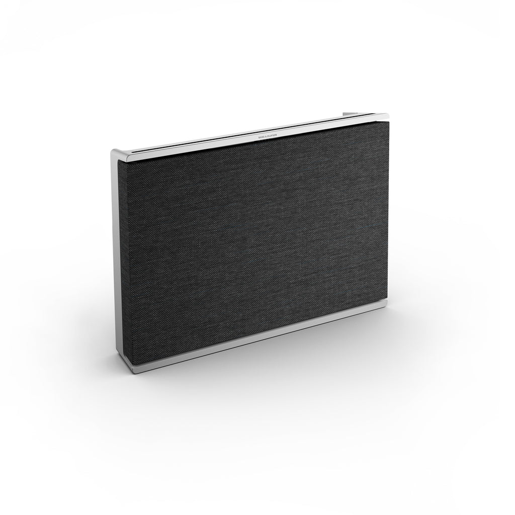 Frontale Perspektive der Beosound Level: Minimalistischer High-End-Lautsprecher mit grauem Textilbezug und präzise gefertigtem Aluminium-Gehäuse, konzipiert für Wandmontage oder zum Aufstellen.