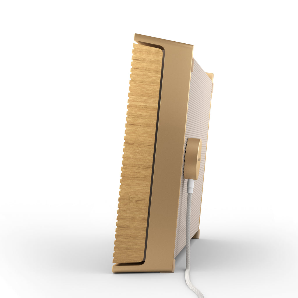 Seitenansicht der Bang & Olufsen Beosound Level in Gold Tone im Hochformat. Gezeigt wird das passende magnetische Ladekabel an der Rückseite und der edle Materialmix aus goldfarbenem Aluminium und hellen Eichenholz-Lamellen.